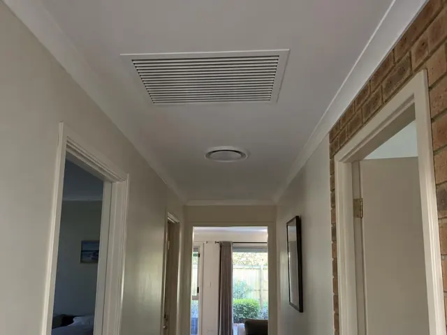 Hallway ceiling with a return-air grille and round outlet in a painted home interior in Maudsland